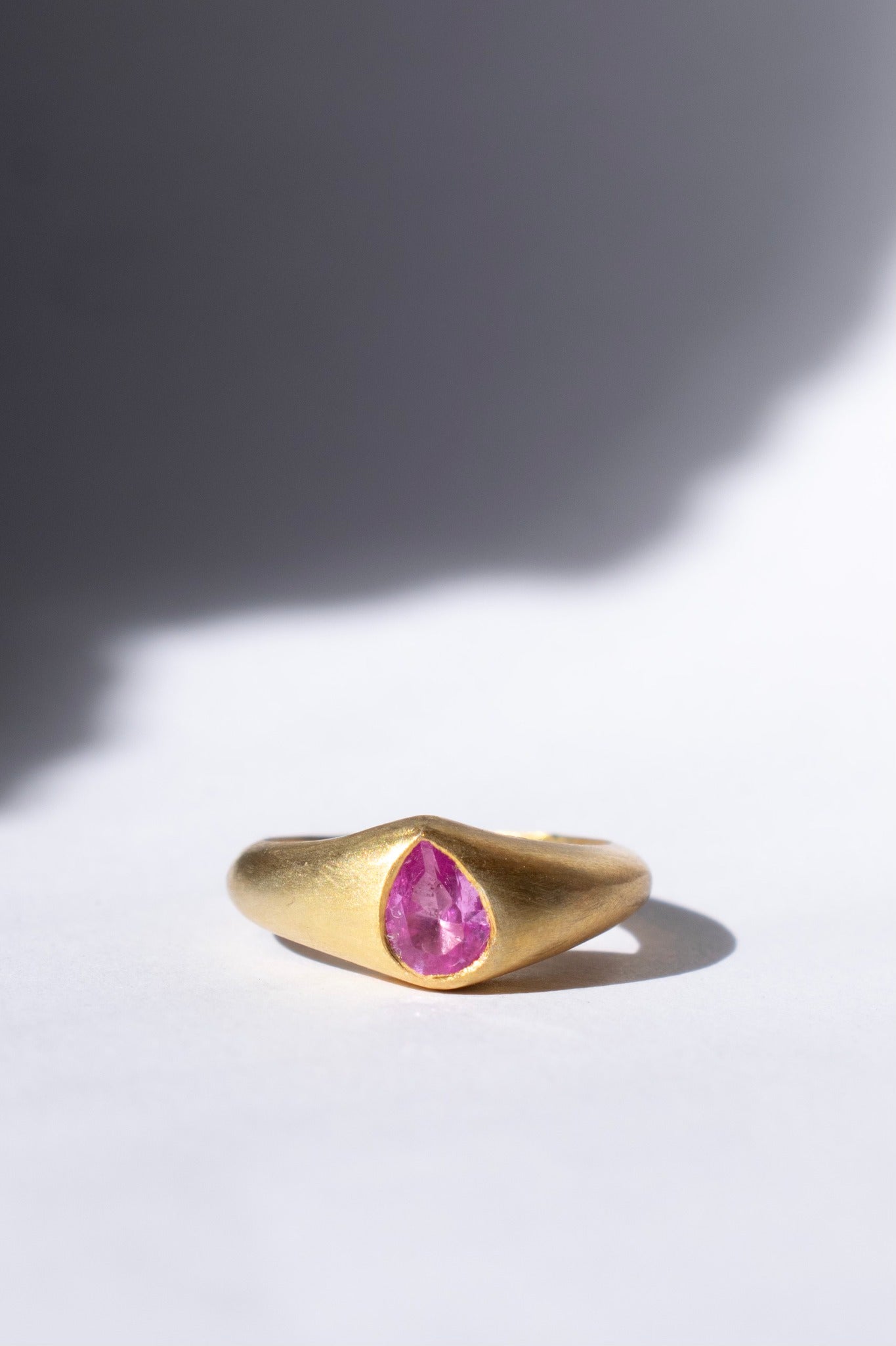 gold and pink sapphire ring on a white background