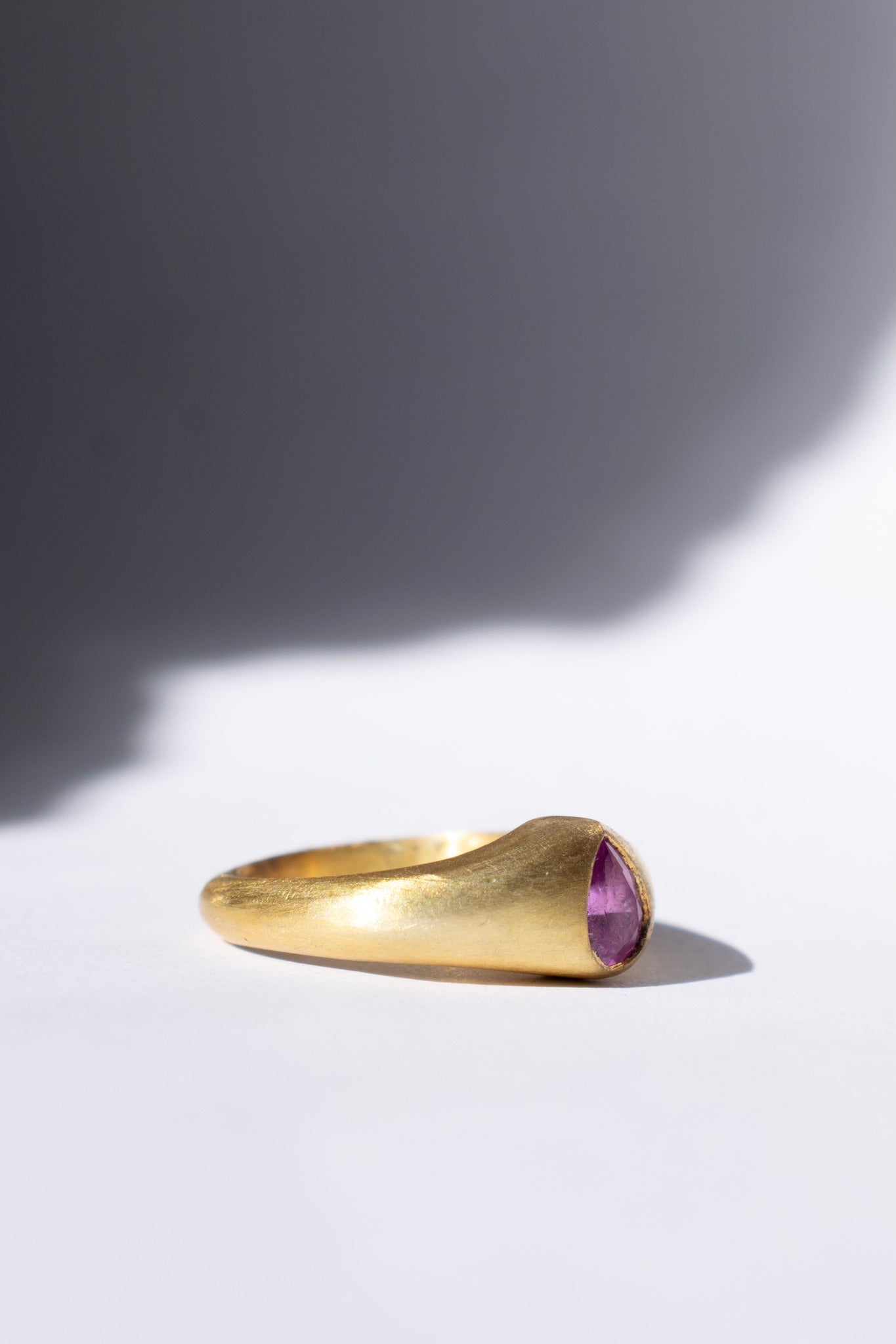 gold and pink sapphire ring on a white background