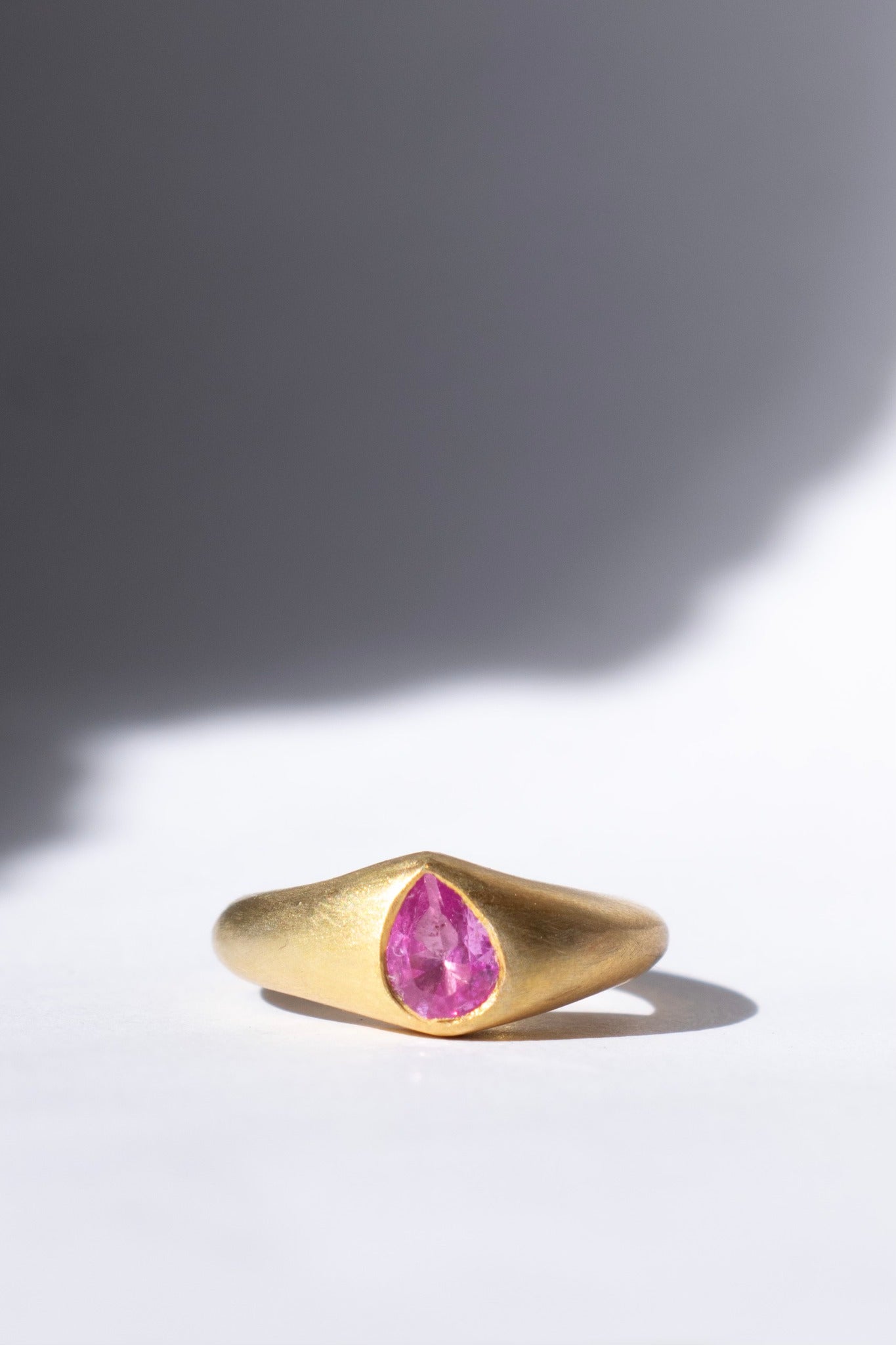 gold and pink sapphire ring on a white background