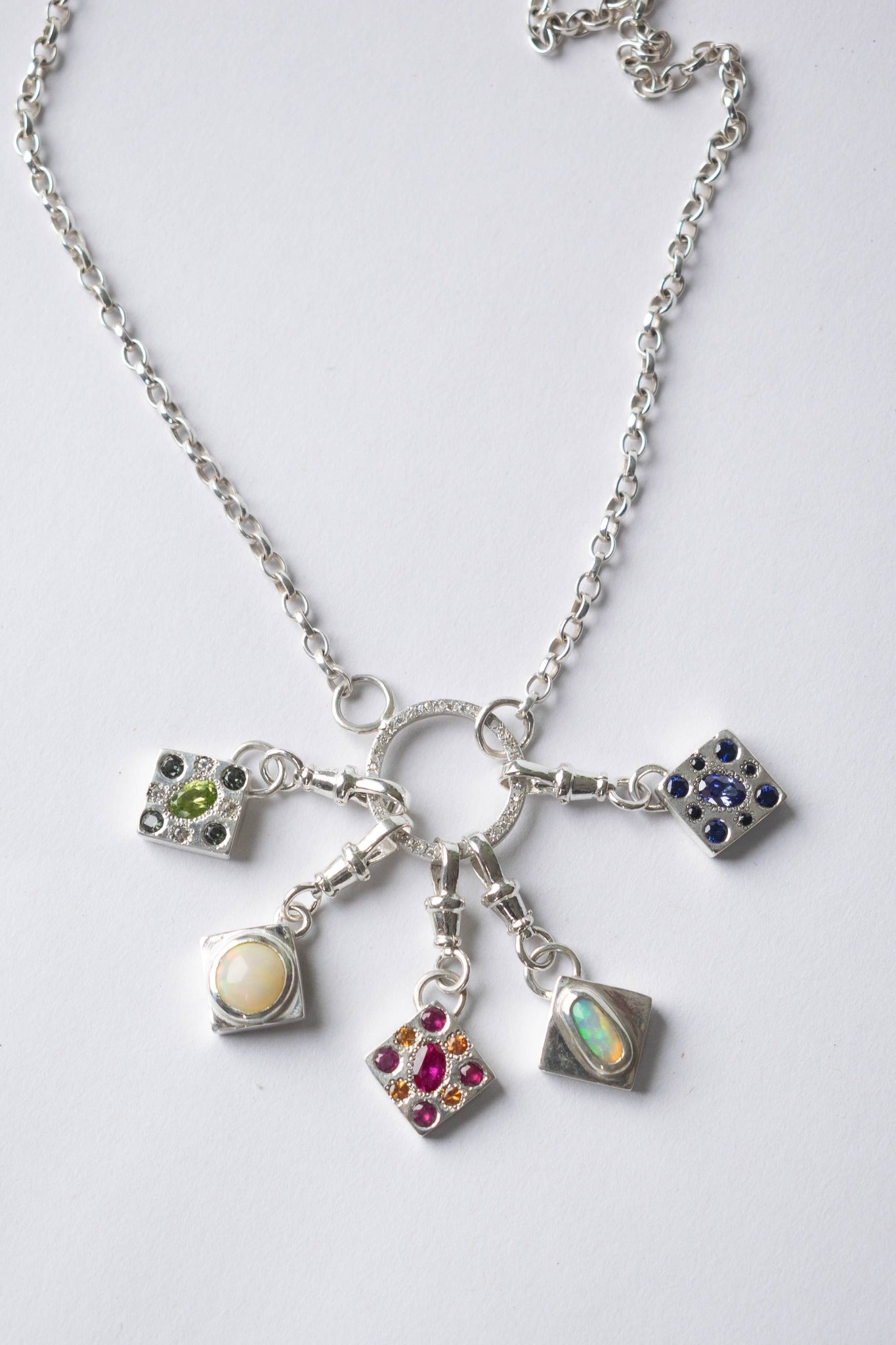 five charms hanging from a necklace on a white background