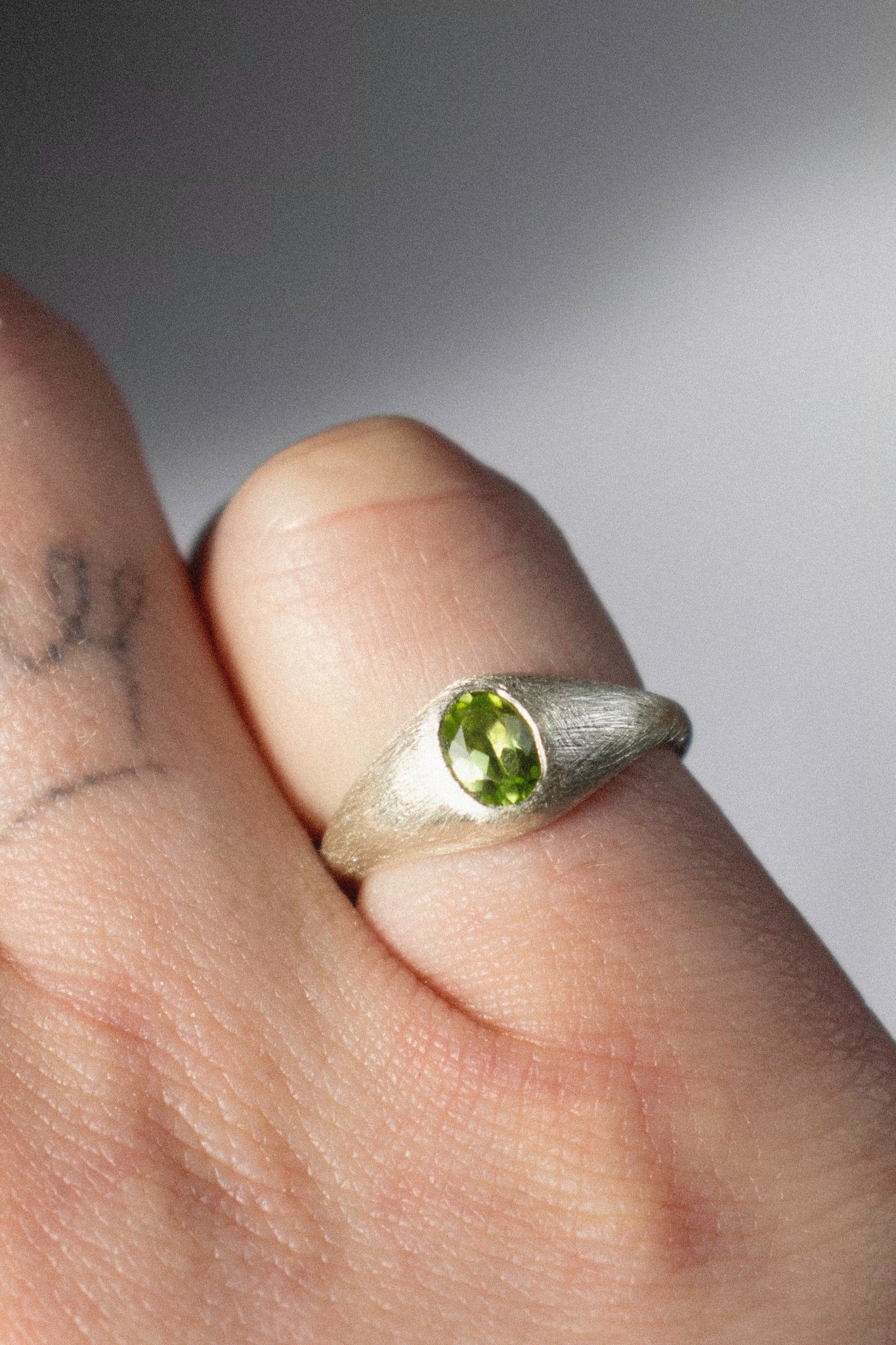 a silver bombé ring with a green peridot on a hand