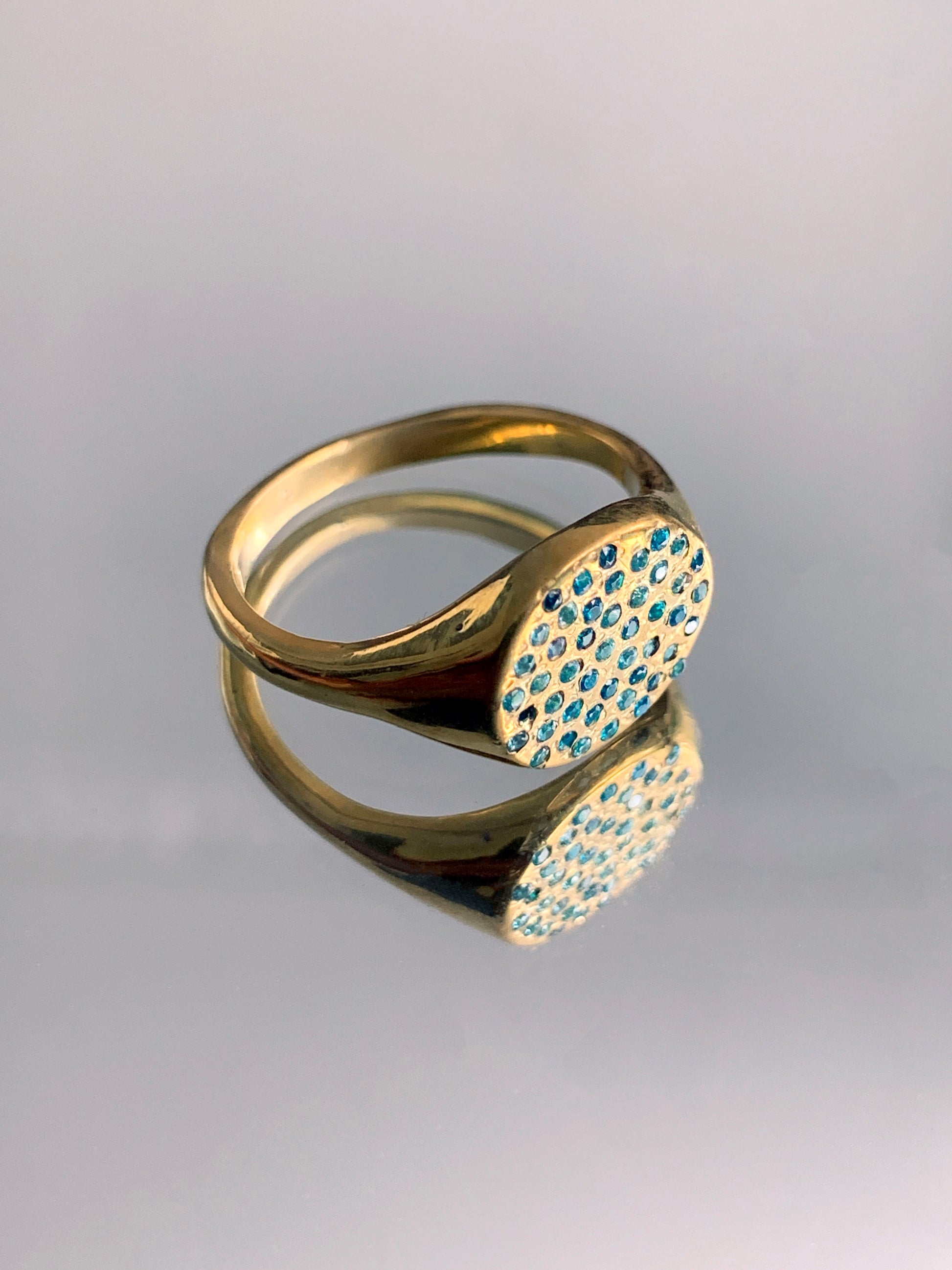 gold signet ring with blue gemstones on a mirror