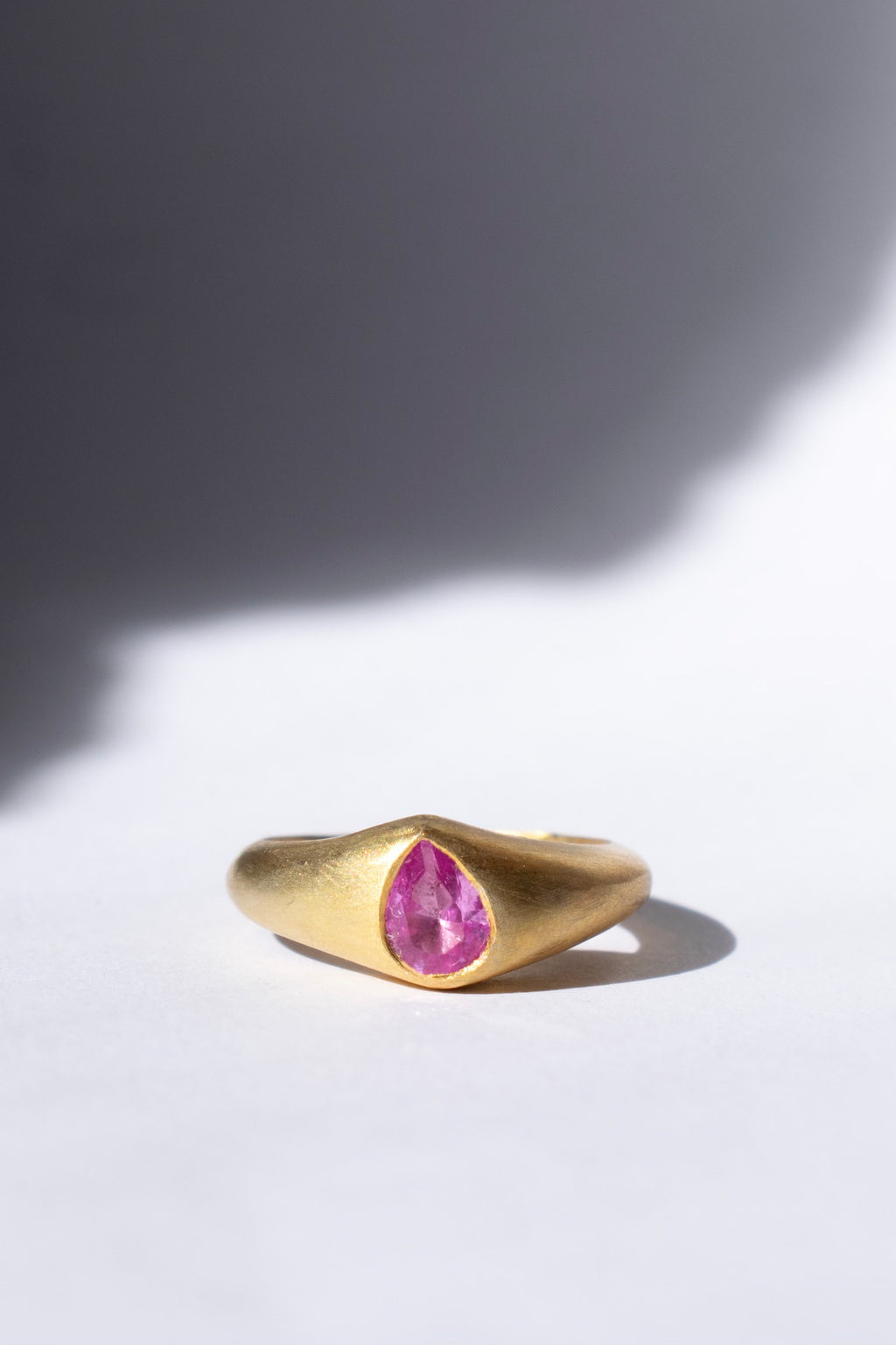 gold and pink sapphire ring on a white background 