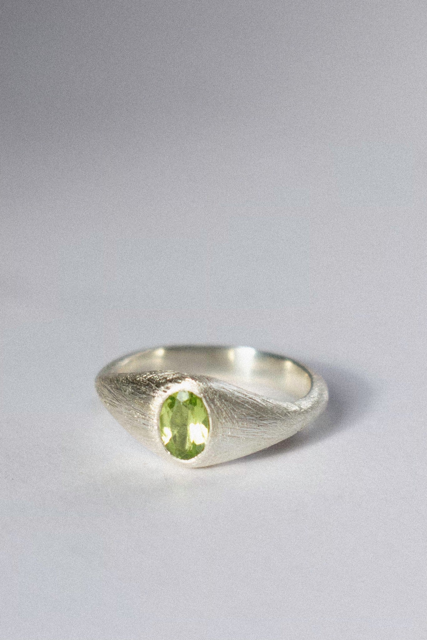a silver bombé ring with a green peridot on a white background