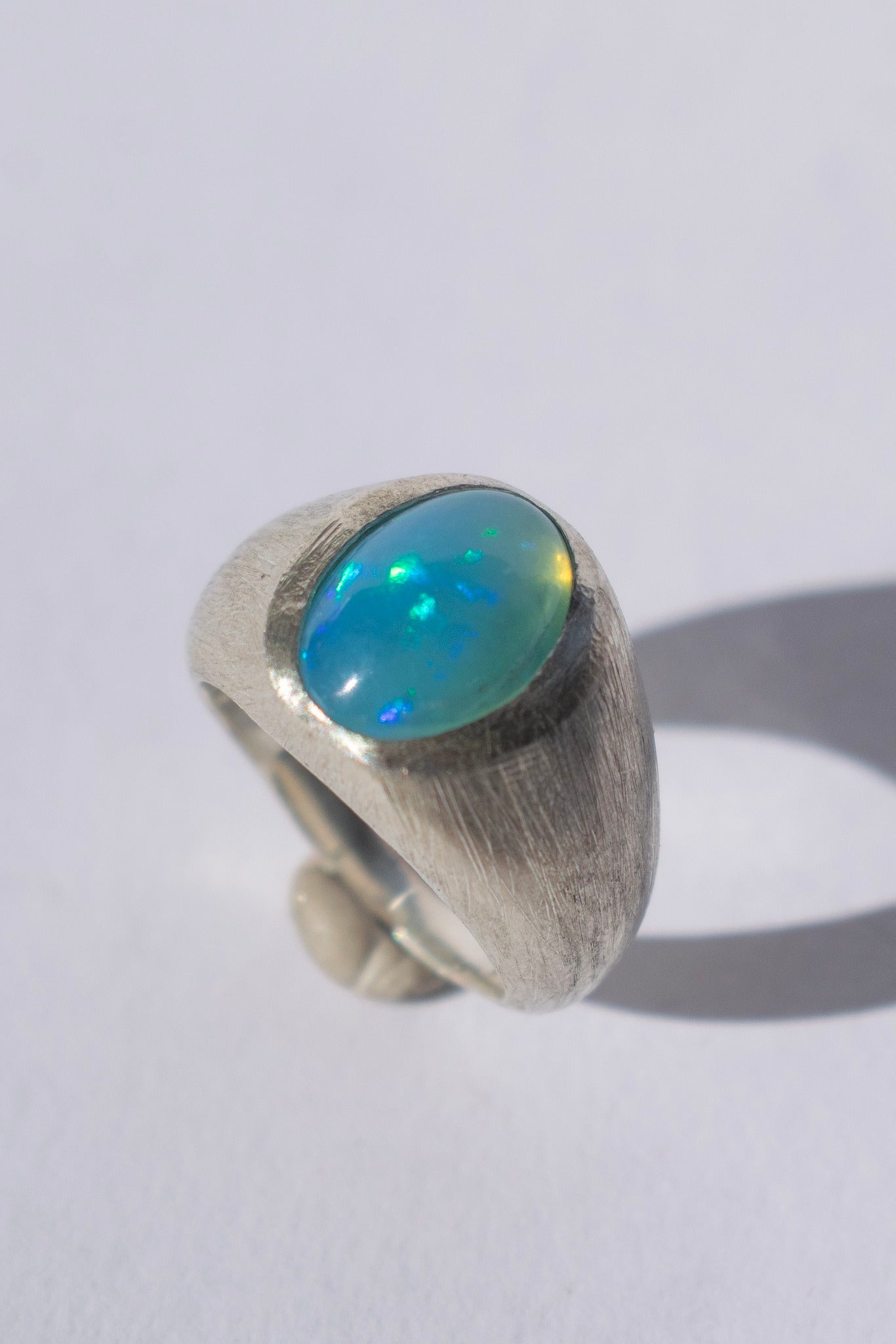 a large silver signet ring with a blue opal and white gemstones 