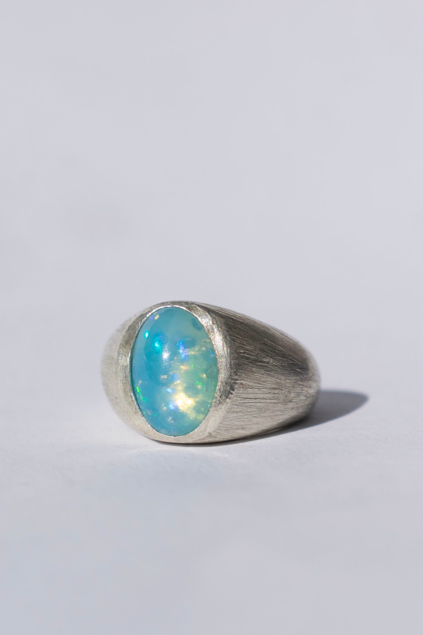 a large silver signet ring with a blue opal and white gemstones on a white background