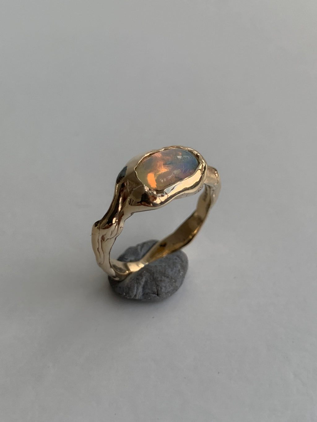 gold and opal engagement ring on a grey background 