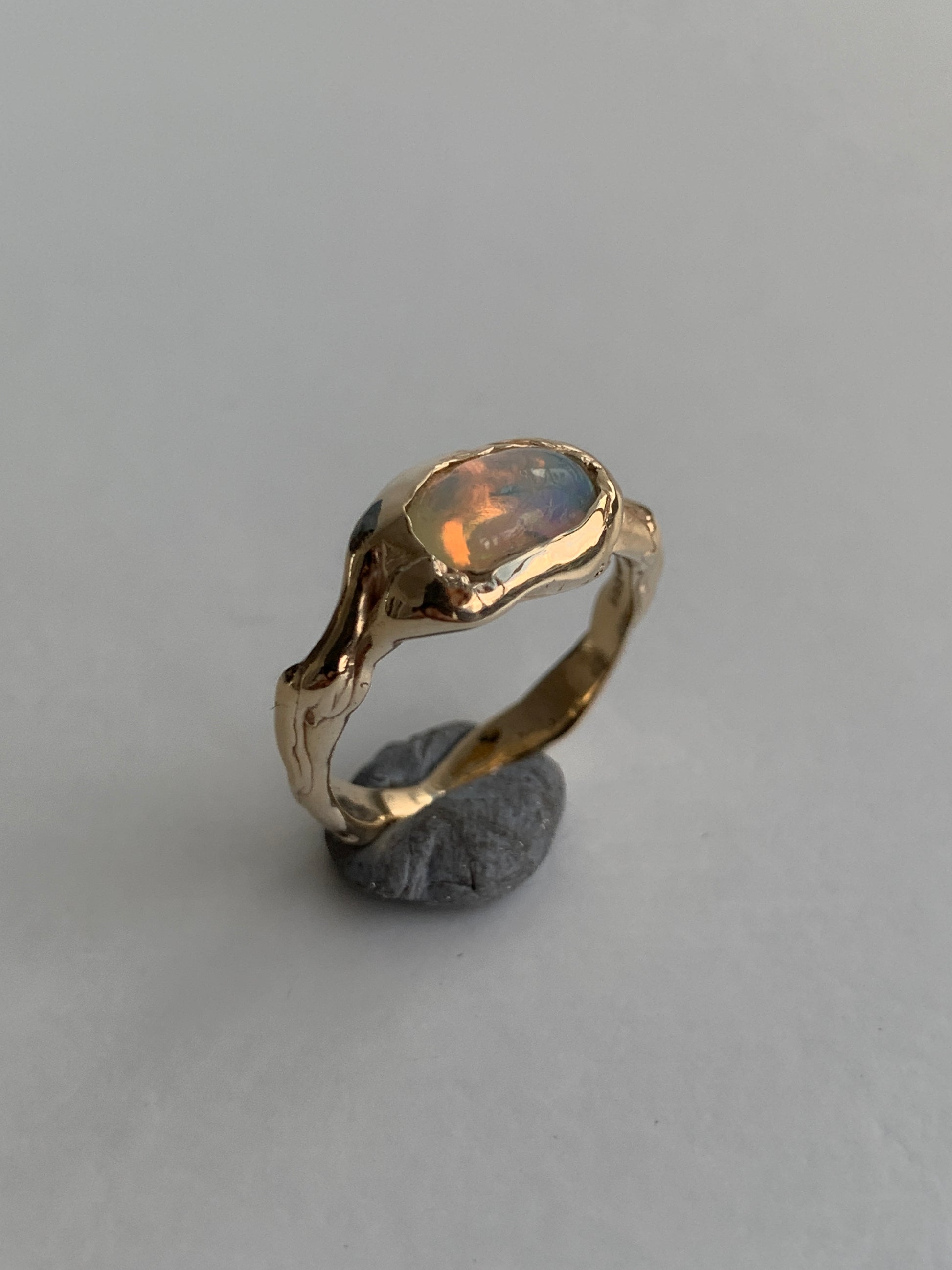 gold and opal engagement ring on a grey background 
