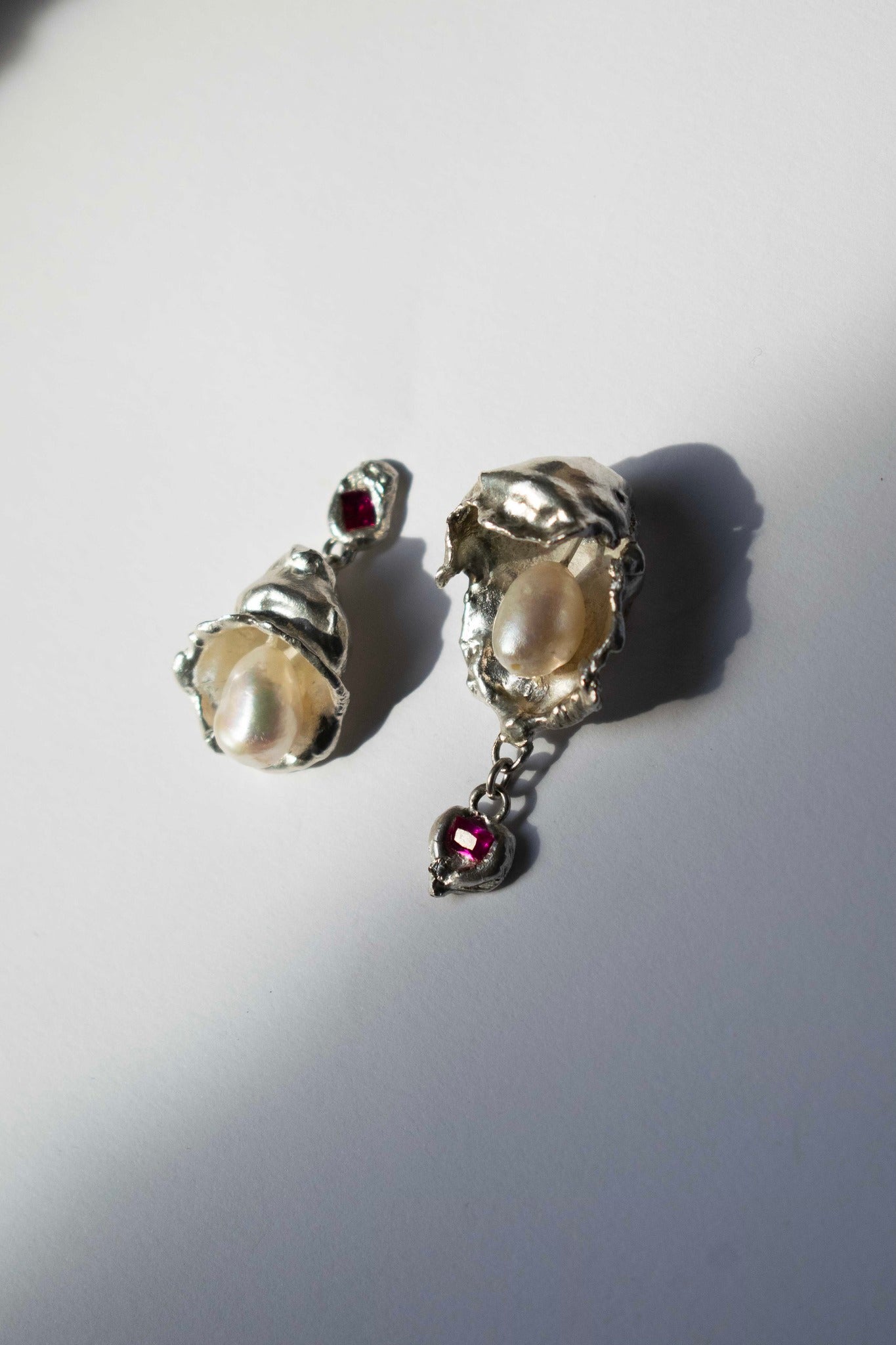 silver earrings with freshwater pearl and ruby on a white background