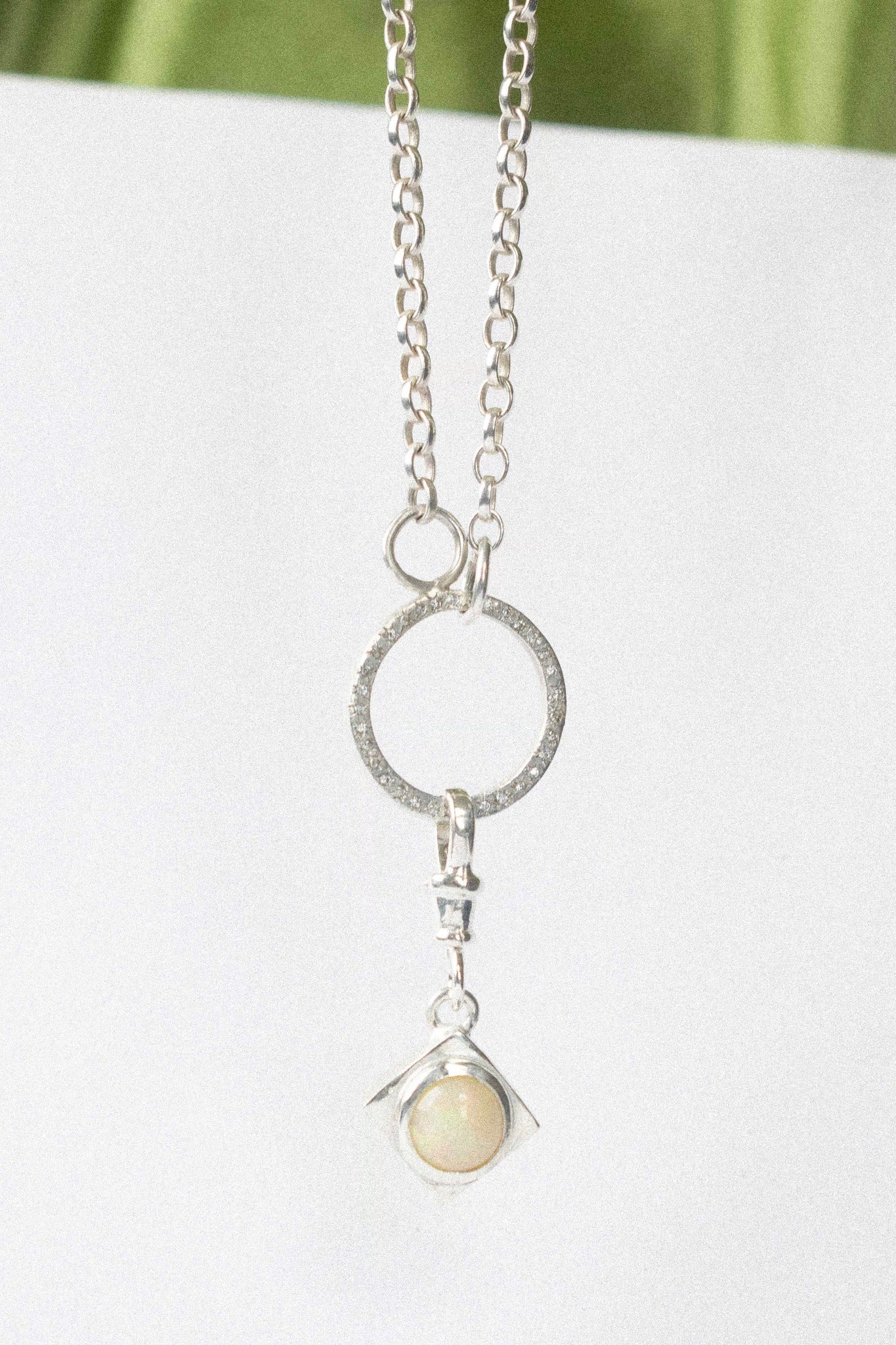 detachable opal charm on a necklace on a white background 