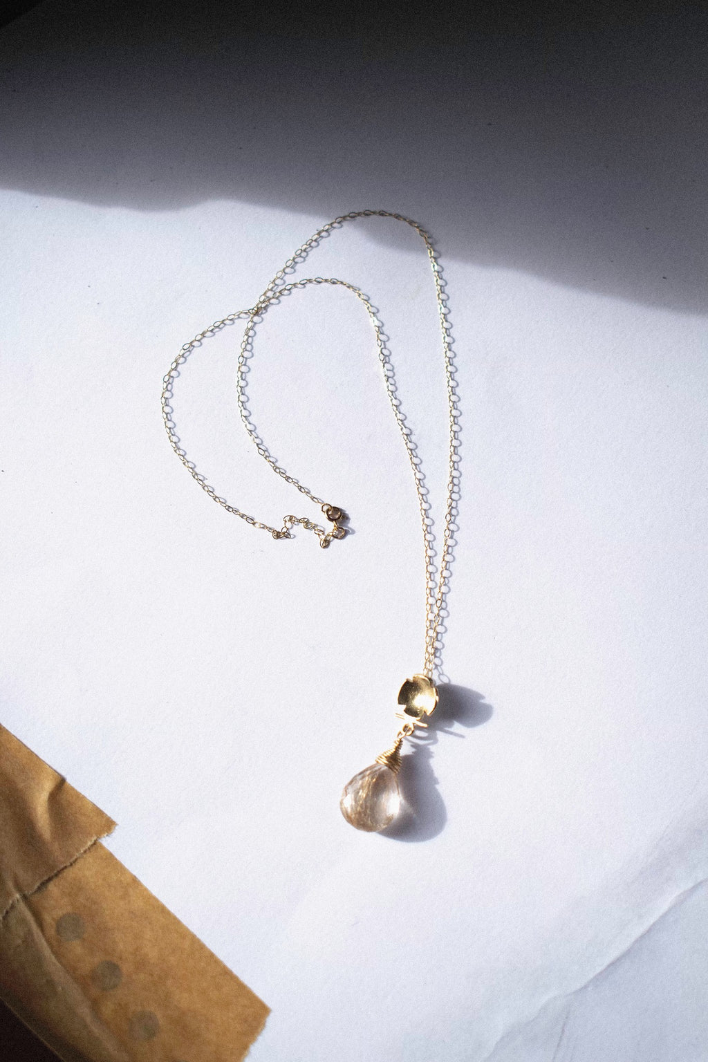 a gold pendant with rutilated quartz on a white background 