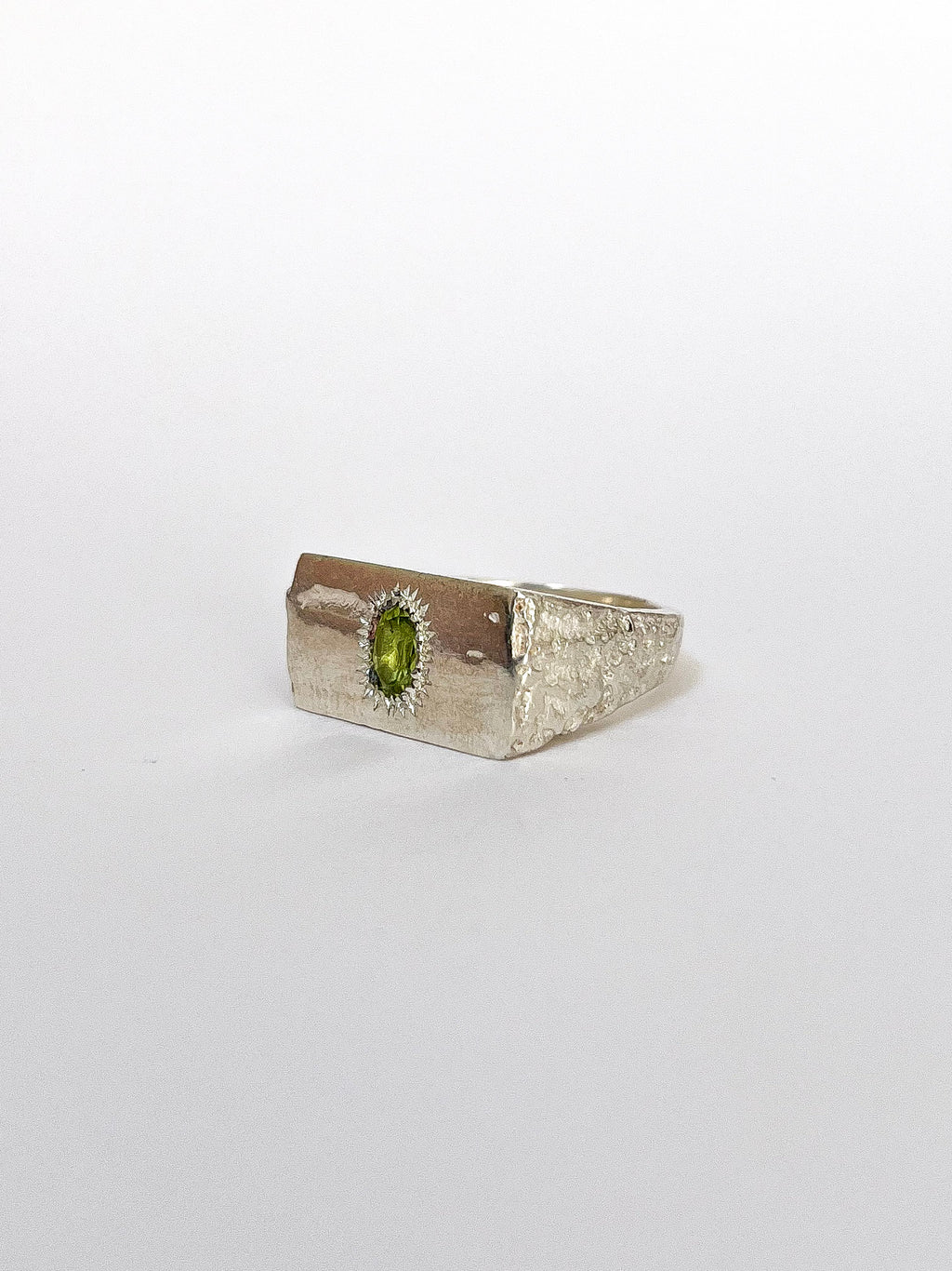 a silver signet ring with peridot on a white background 