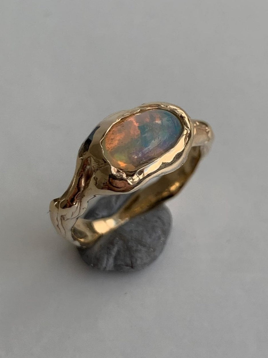 gold and opal engagement ring on a grey background 