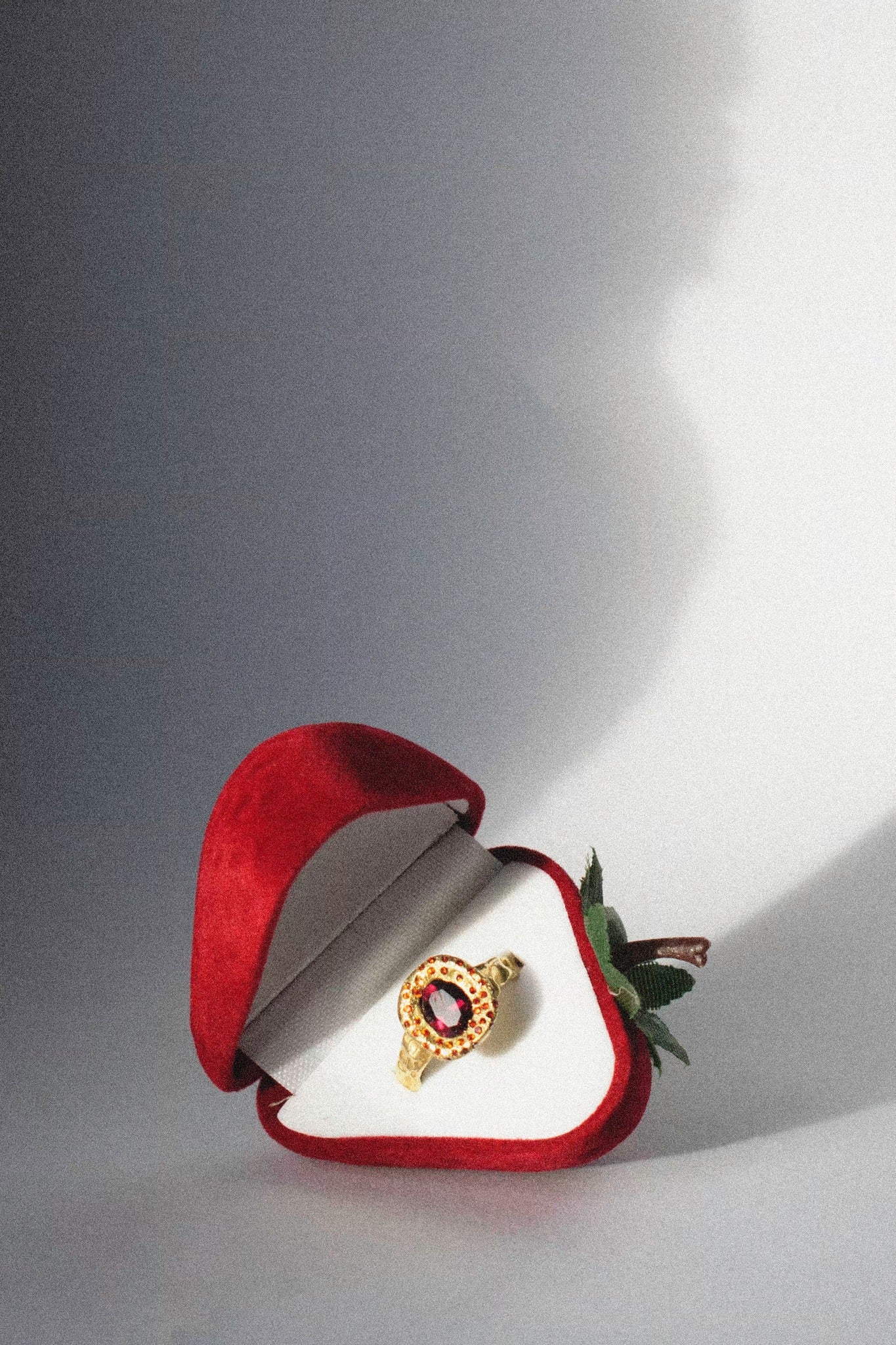 a strawberry ring box with a ring in it on a white background