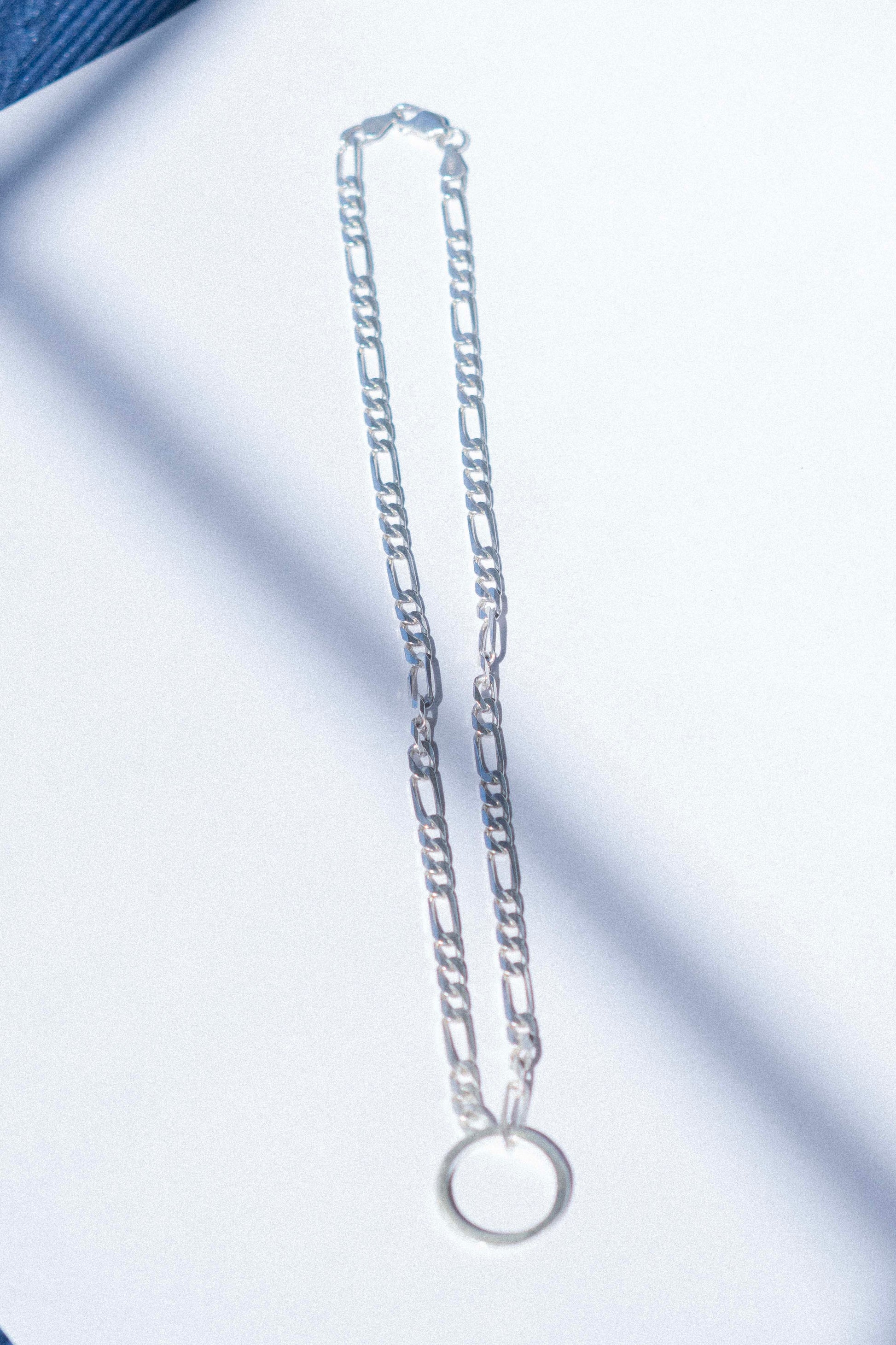a classic silver Figaro chain displayed on a white background 