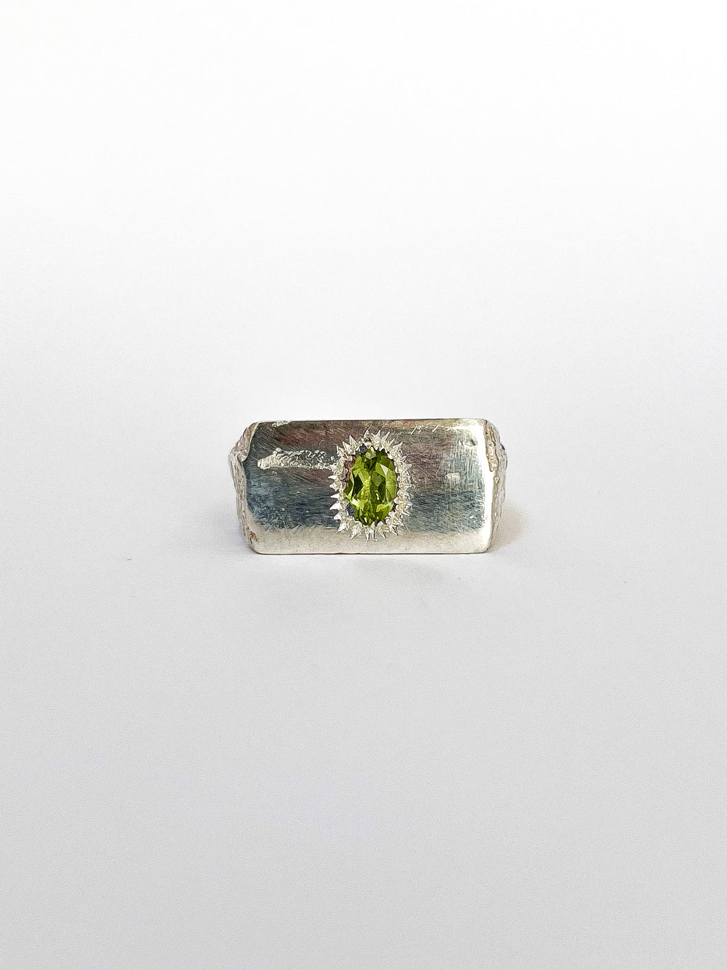 a silver signet ring with peridot on a white background 