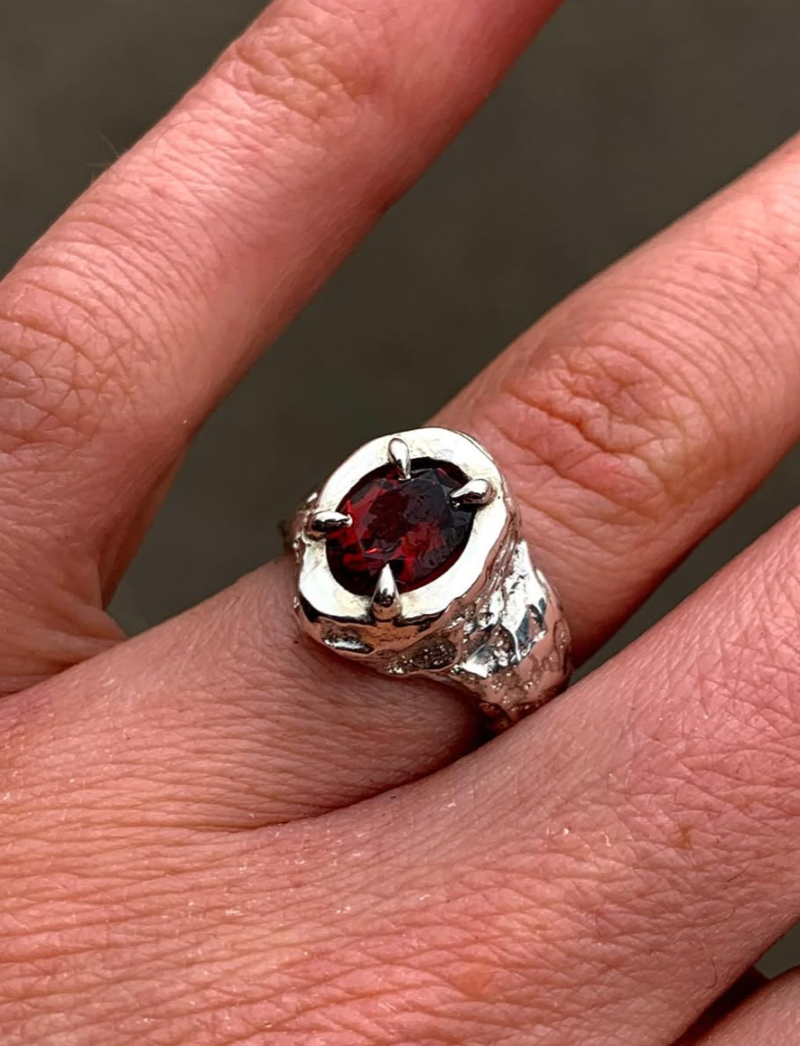 a woman's hand wearing a silver and red ring
