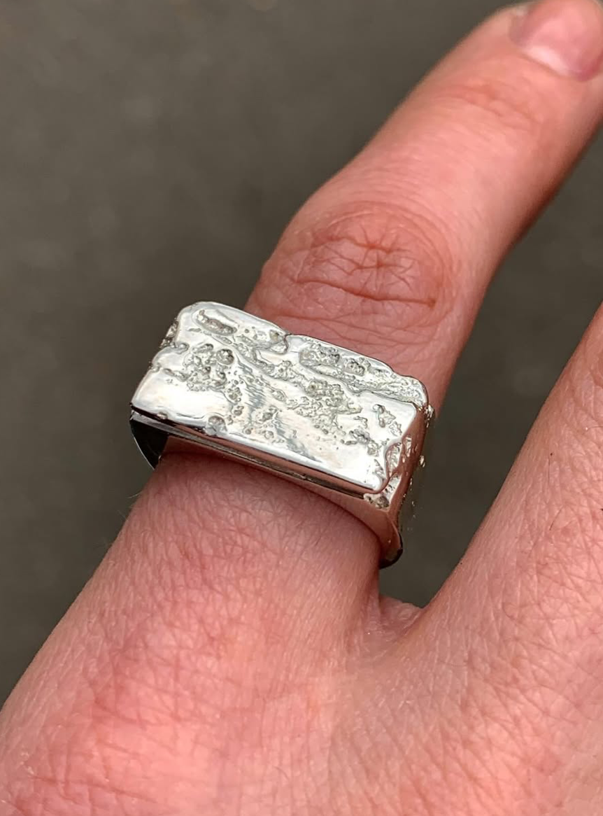 silver signet ring worn on a woman's hand