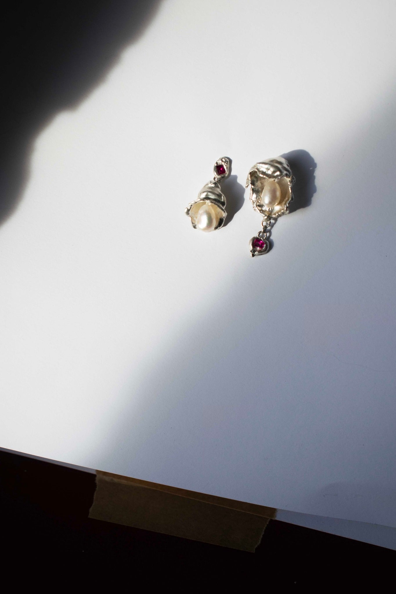 silver earrings with freshwater pearl and ruby on a white background