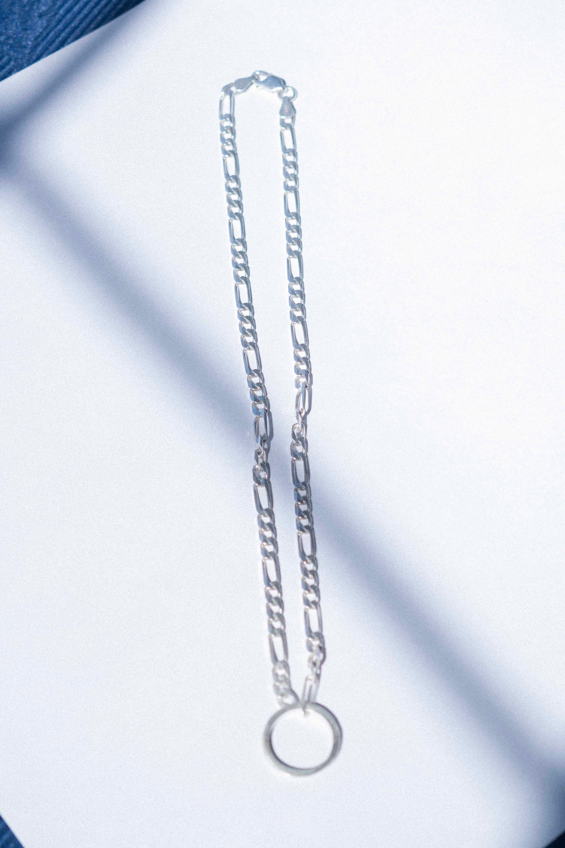 a classic silver Figaro chain displayed on a white background 