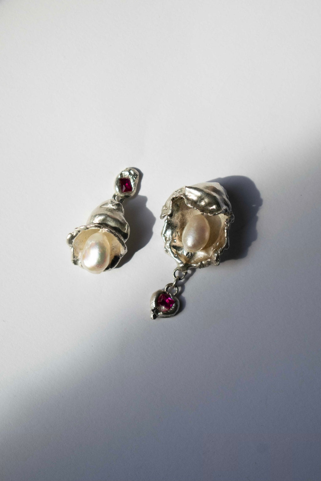 silver earrings with freshwater pearl and ruby on a white background