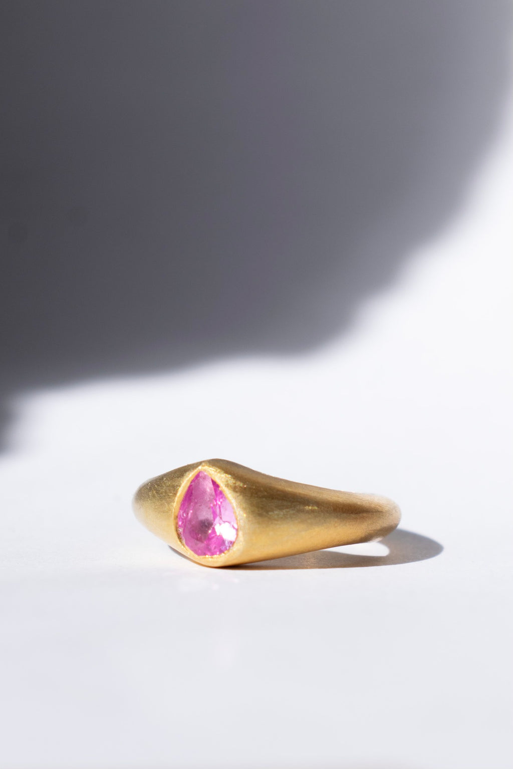 gold and pink sapphire ring on a white background 