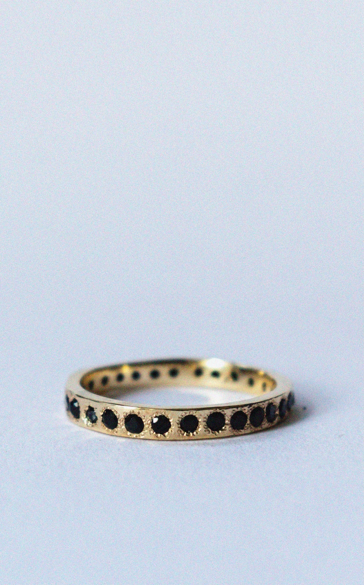gold and spinel eternity band on a white background 