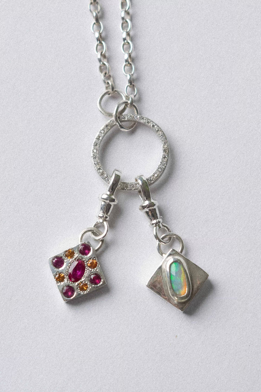 two charms hanging from a necklace on a white background
