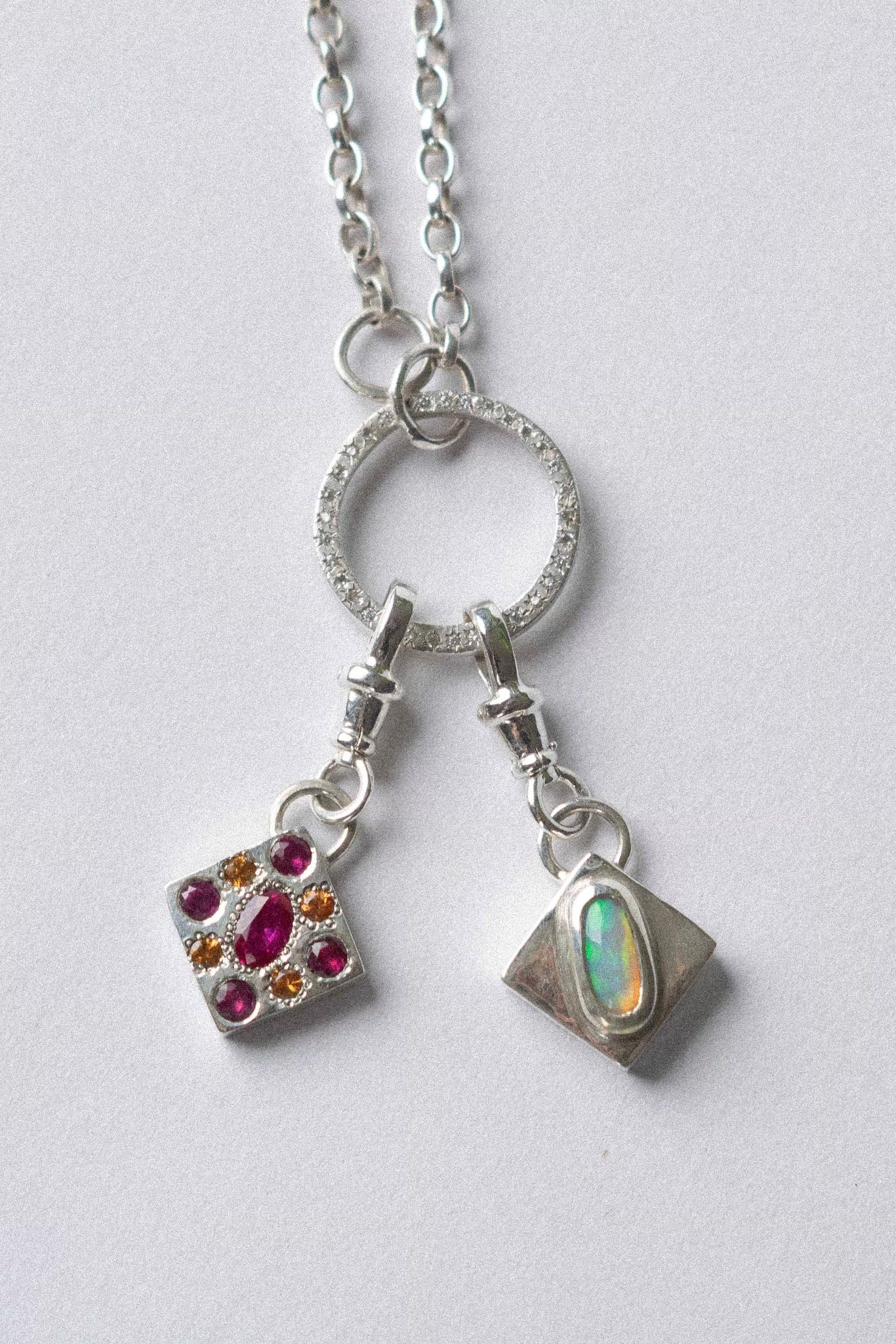 two charms hanging from a necklace on a white background