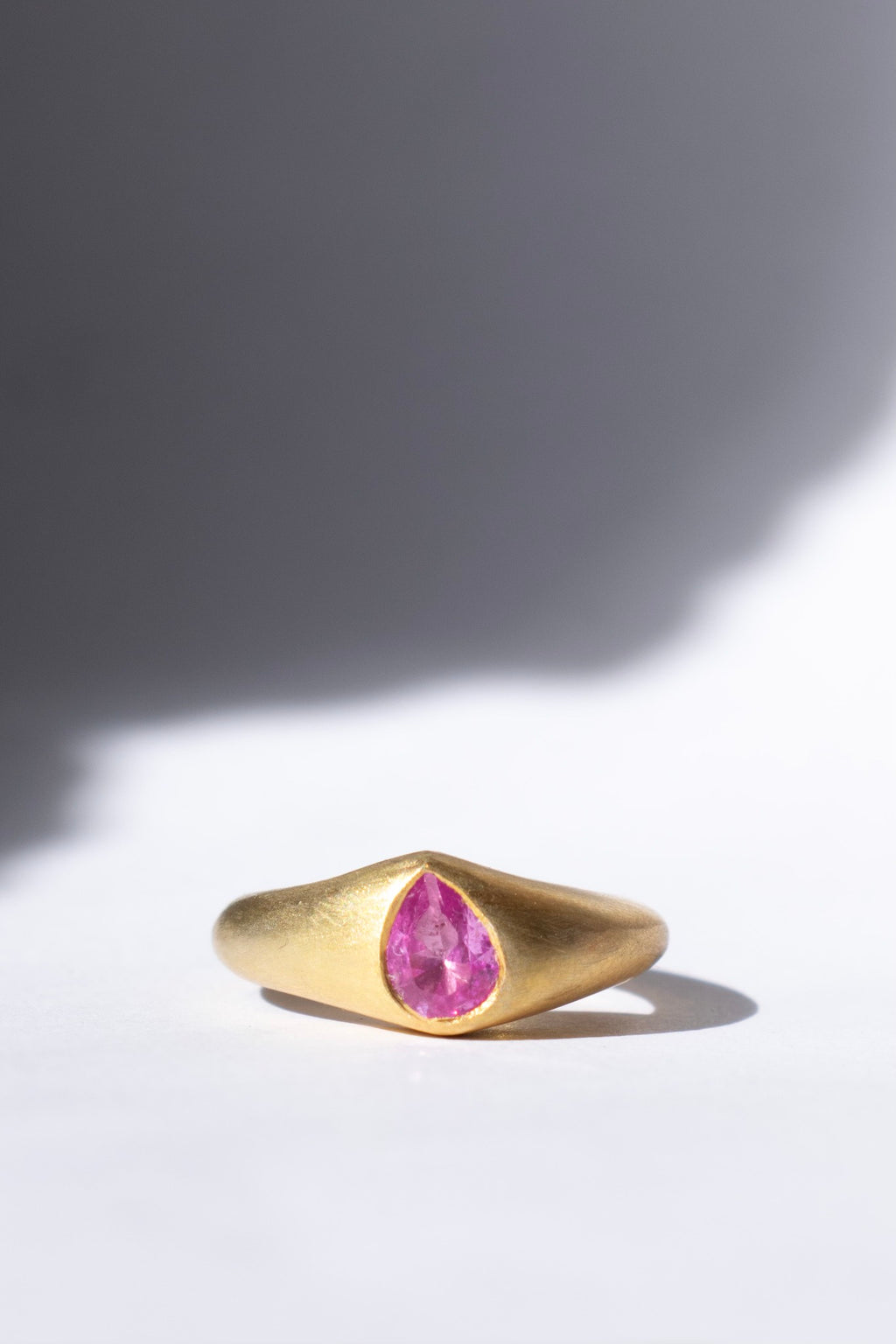 gold and pink sapphire ring on a white background 