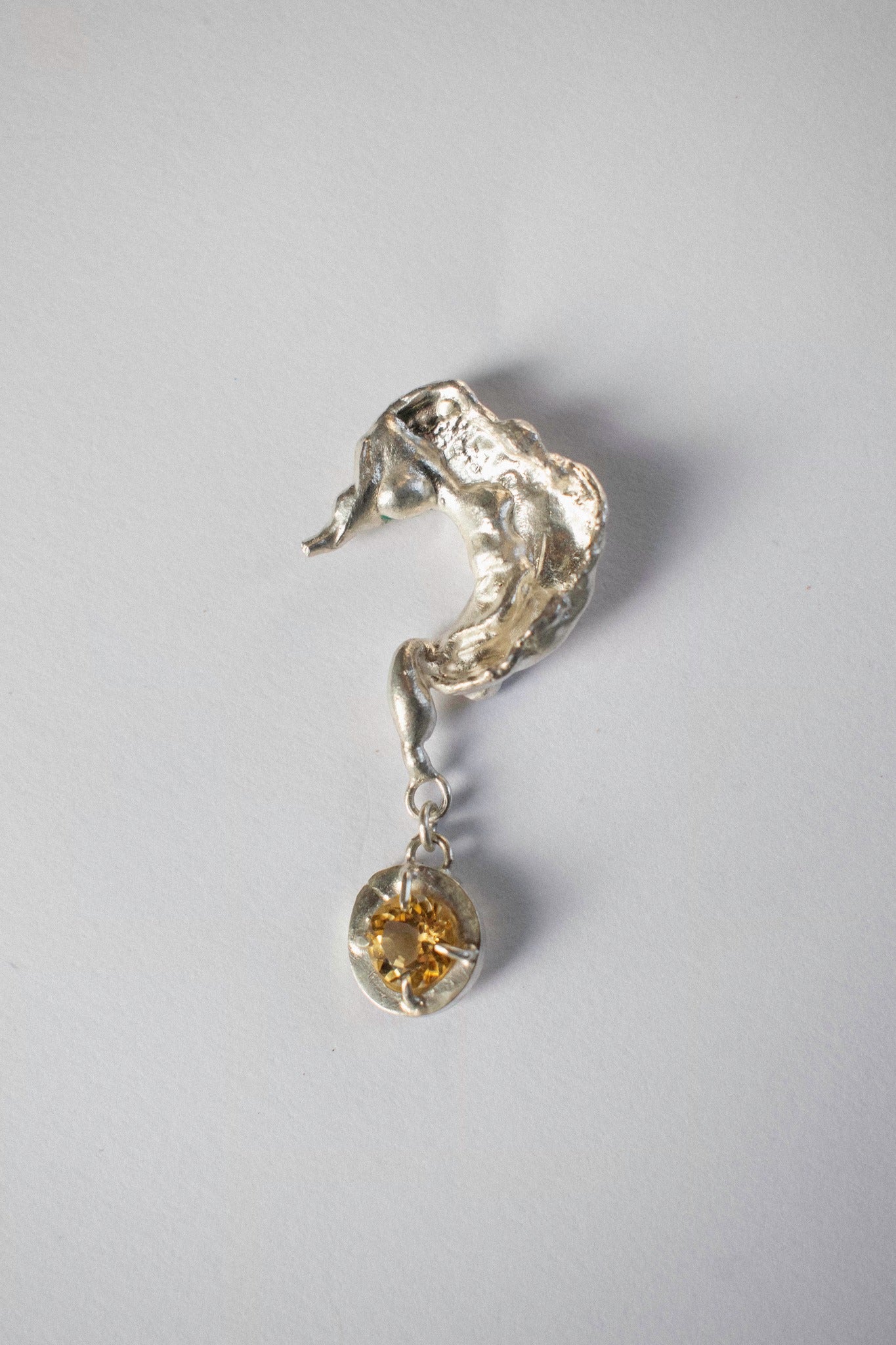 silver earring in the shape of a question mark on a white background