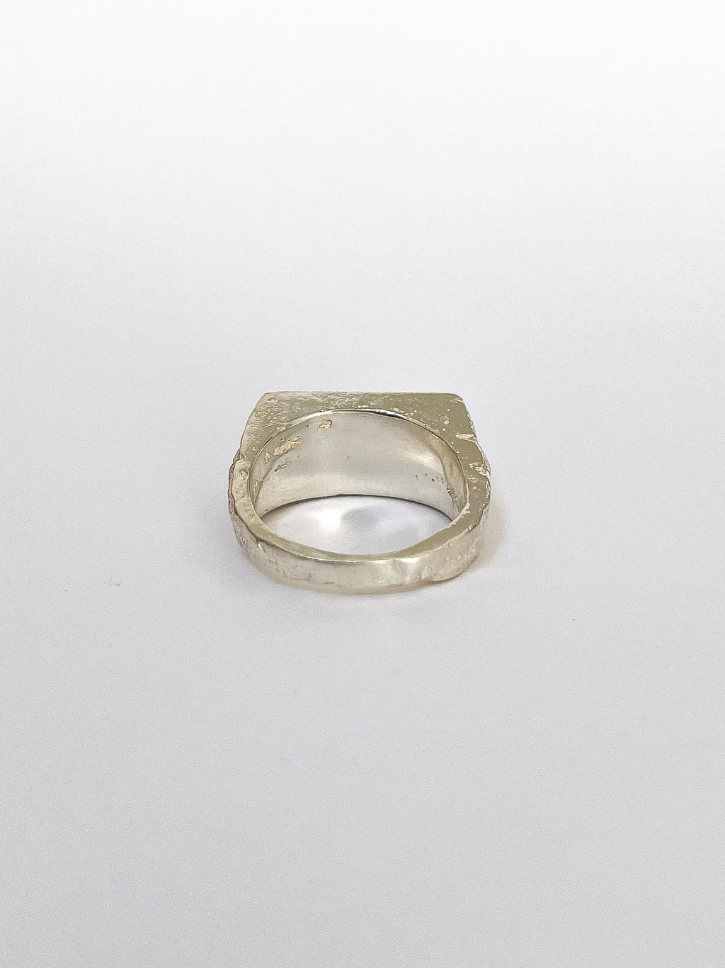 a silver signet ring with peridot on a white background 