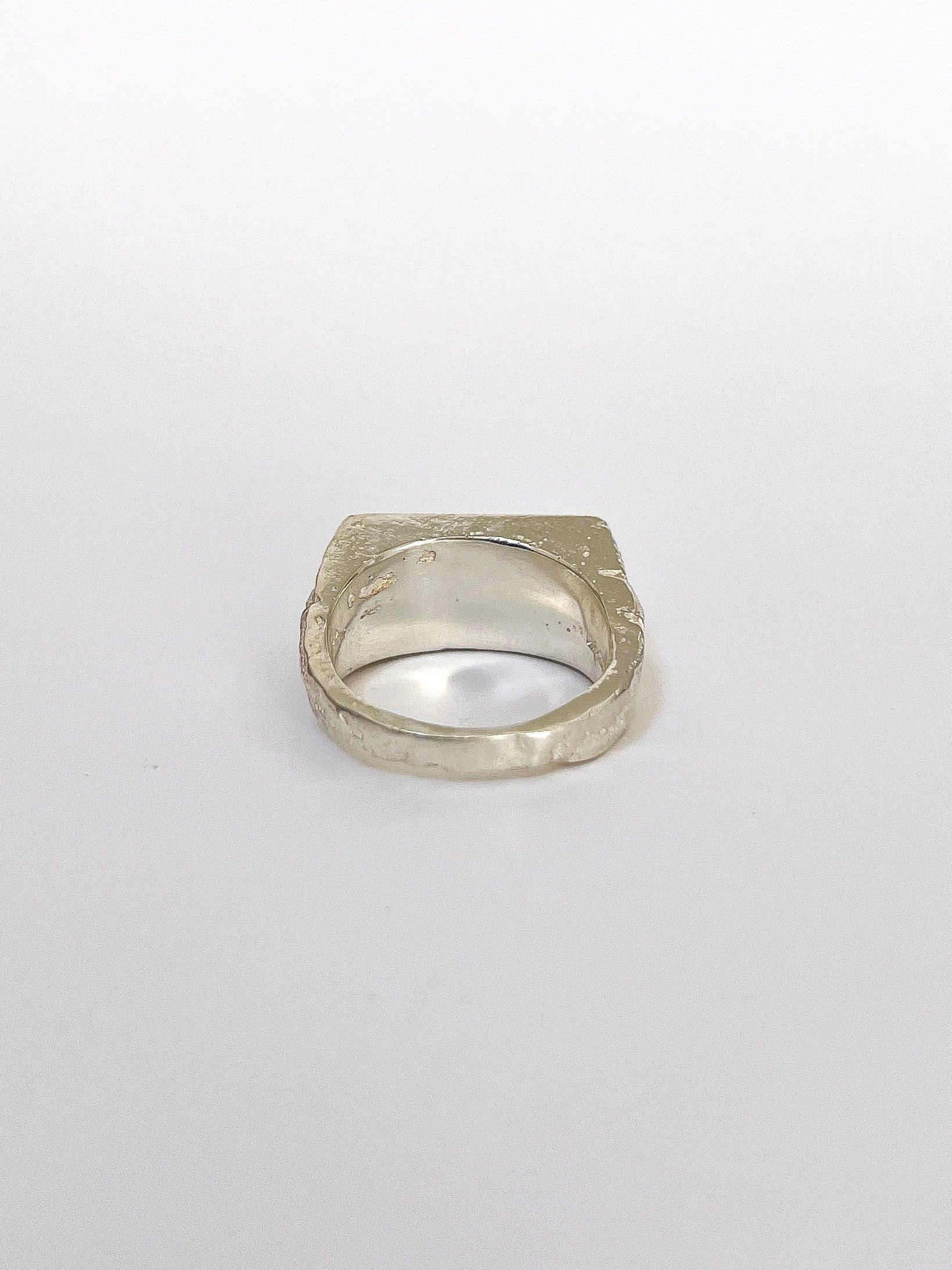 a silver signet ring with peridot on a white background 