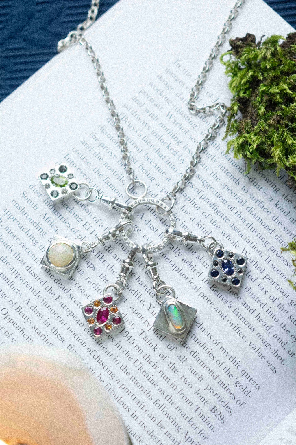 5 charms hanging from a necklace on a book text background