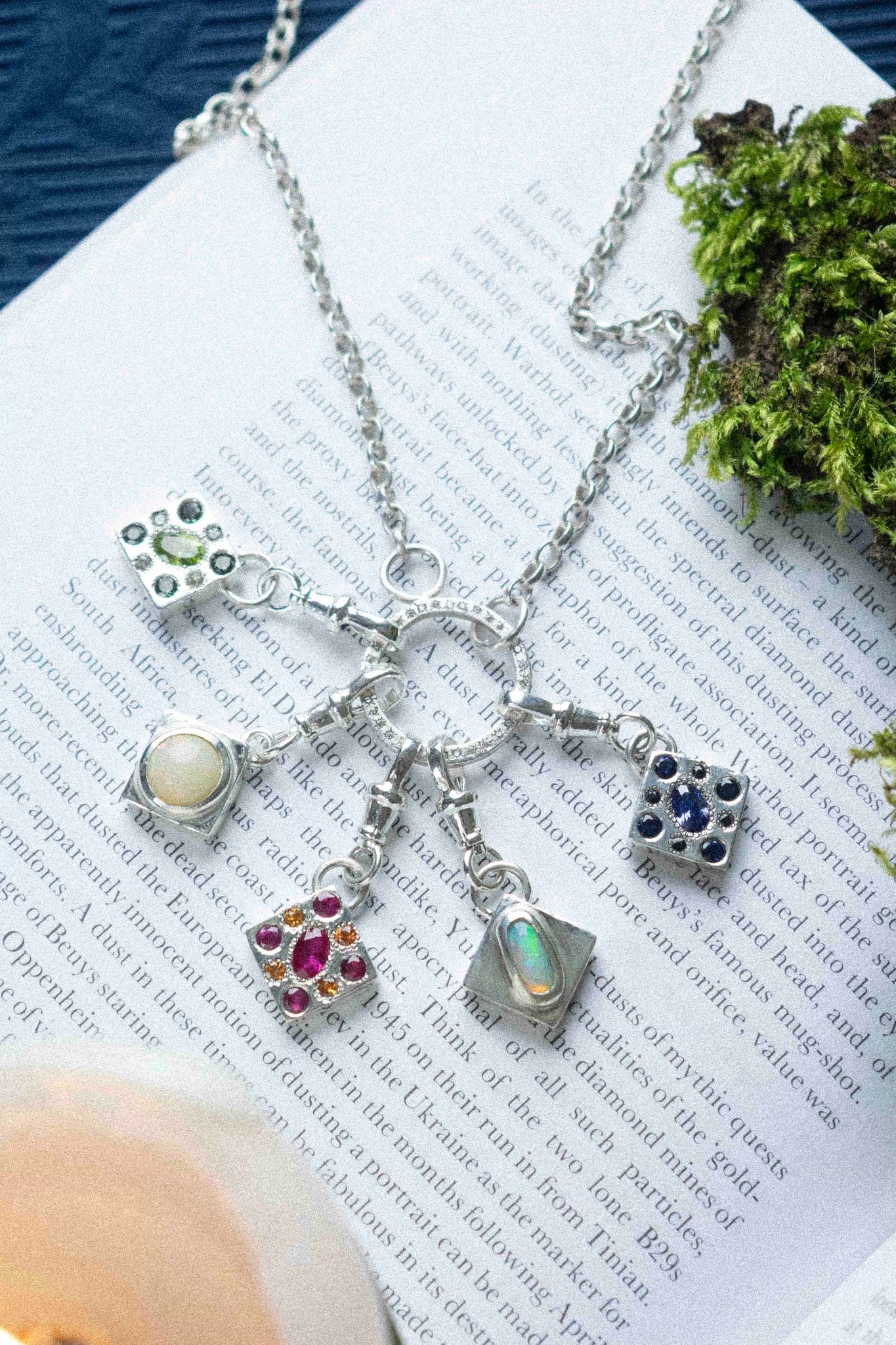 5 charms hanging from a necklace on a book text background