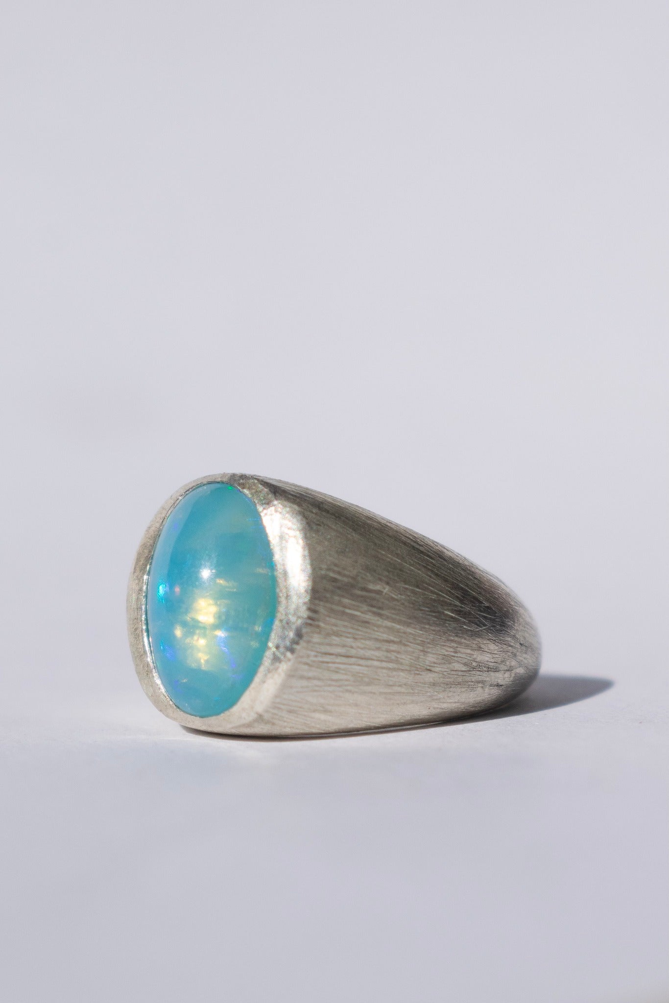 a large silver signet ring with a blue opal and white gemstones 