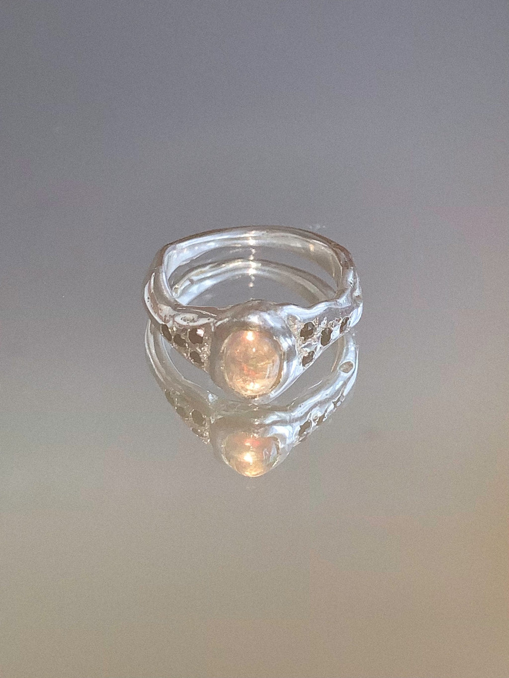 silver and opal ring on a mirror