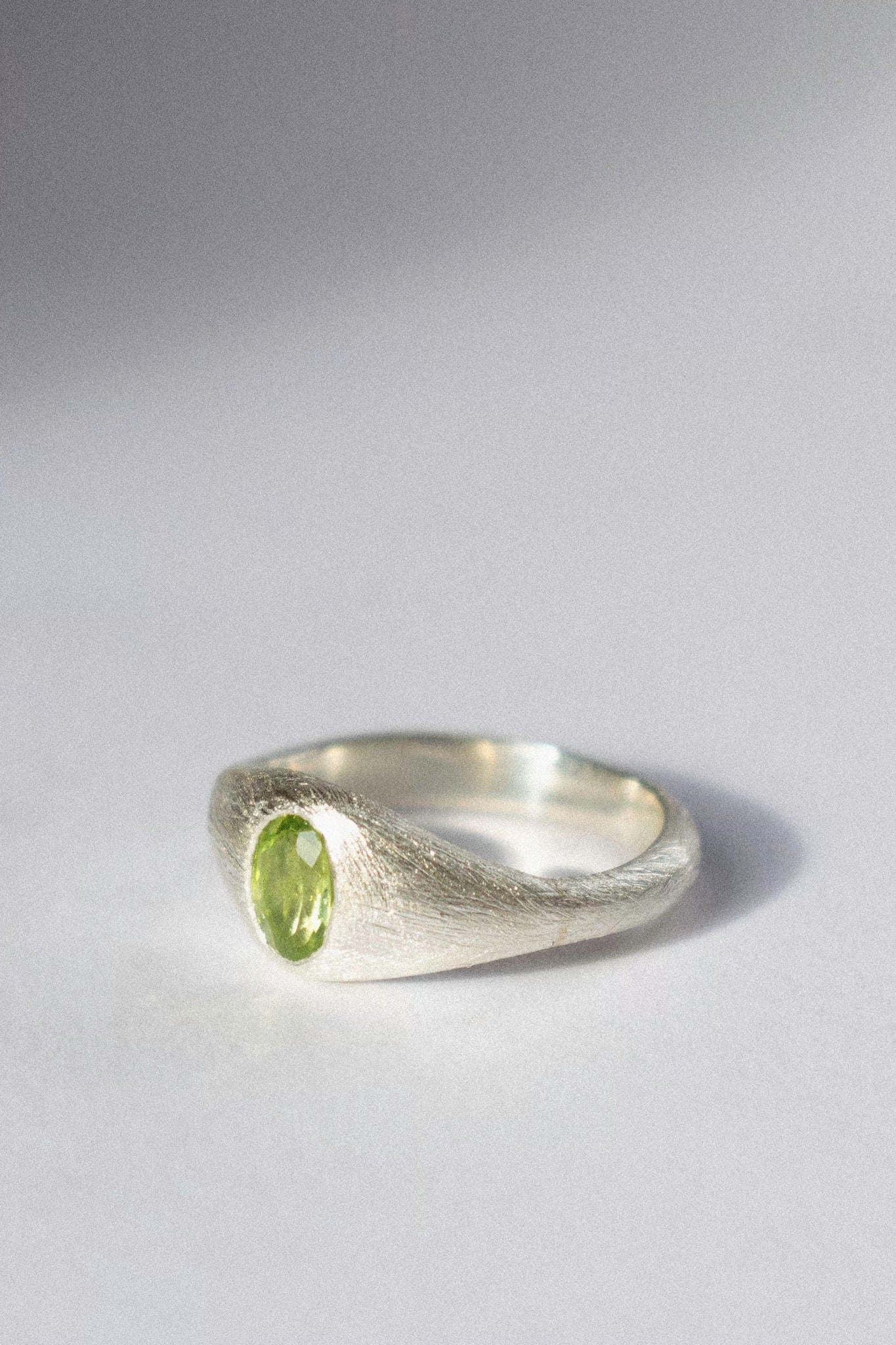 a silver bombé ring with a green peridot on a white background